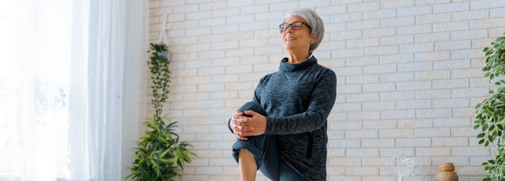 Woman exercising and stretching holding knee to chest