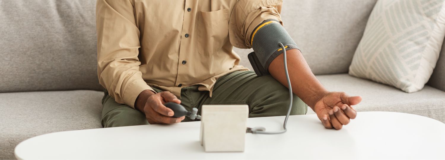 Man taking blood pressure reading with cuff on couch