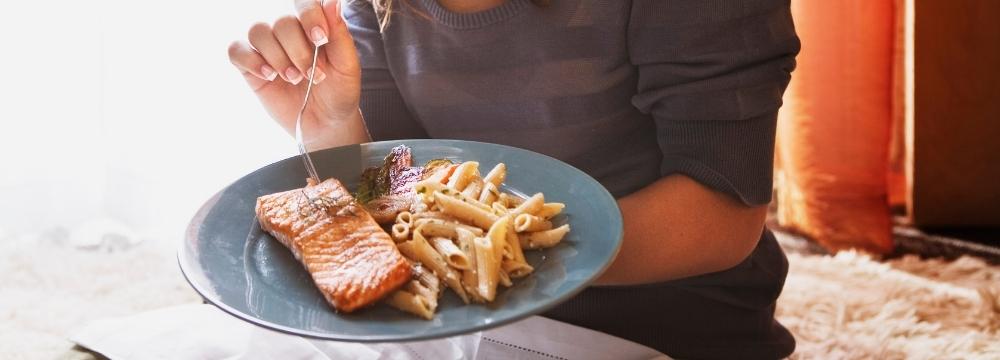 woman eating healthy fatty salmon with carbs in moderation