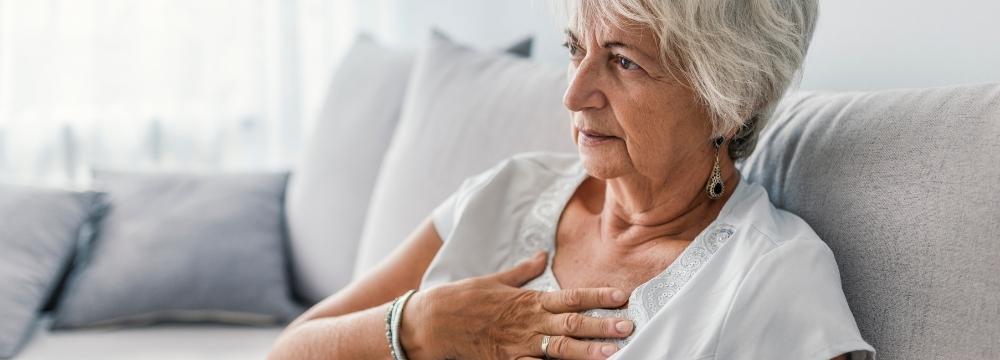 Woman reaching for chest lying on couch