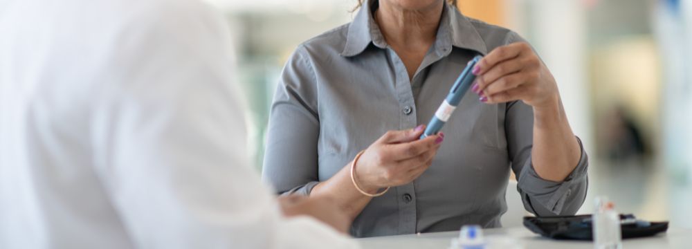 Woman holding injection while talking with doctor