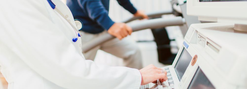 man on treadmill during stress test with cardiologist controlling panel