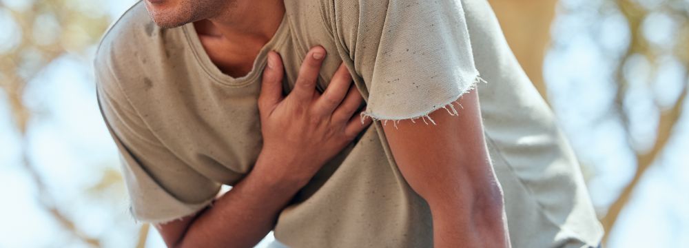 Man grabbing chest with one hand while hunched over