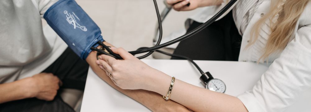 Man getting blood pressure taken by doctor with arm on table