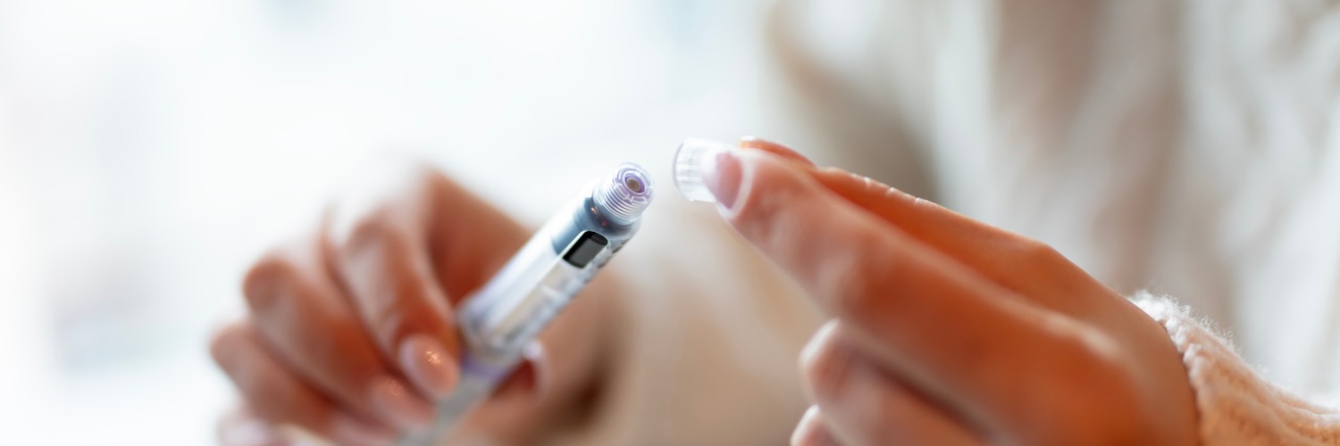 Woman taking cap off of injection with elbows on wooden table 